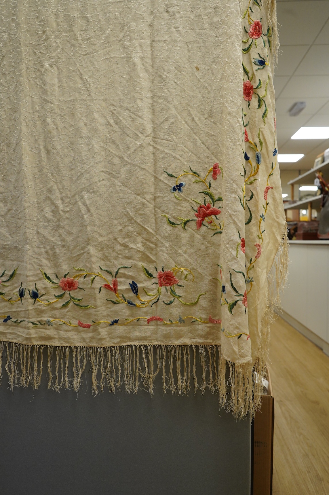 An early Chinese 20th century cream silk damask shawl with a polychrome floral silk embroidered border and a silk fringe, 150cm x 150cm, together with a smaller shawl/scarf, the corner cream on cream embroidered and edgi